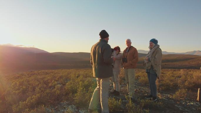 日出时分，野生动物园旅行团在阳光明媚的偏远风景中交谈