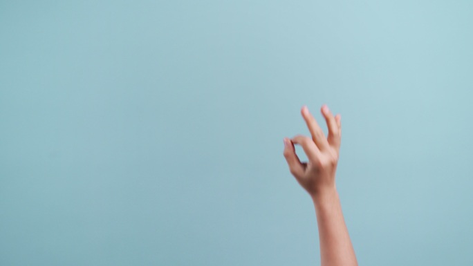 女人的手在复印空间上用手指做“OK”手势，在蓝色背景下移动手势