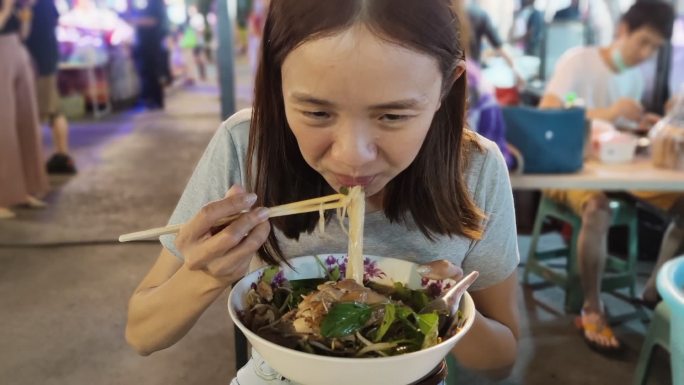 泰国街头吃面条的女人