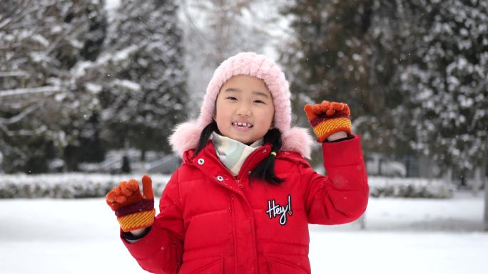 小女孩在冬天快乐地挥手和竖起大拇指