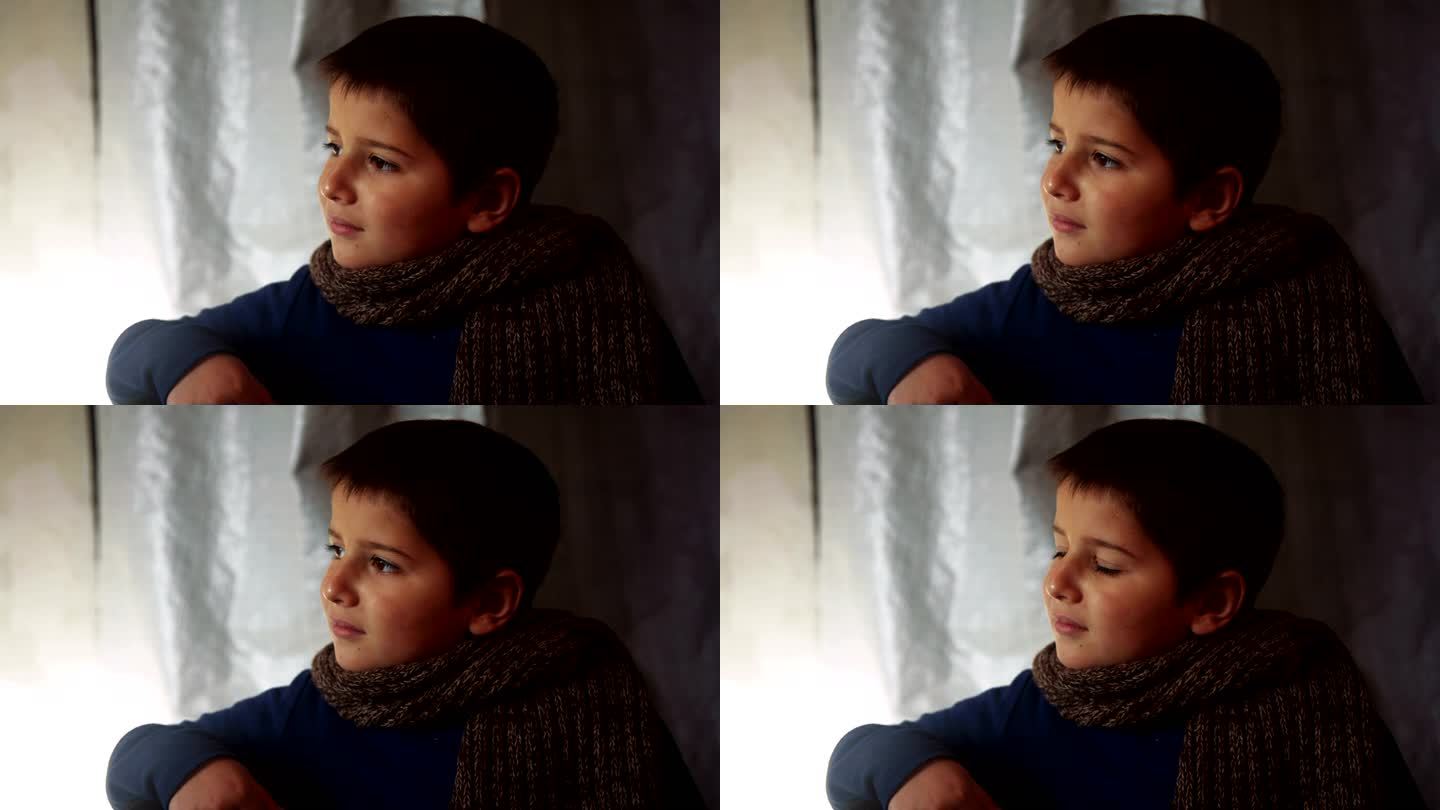 戴着围巾的男孩坐着看着窗外