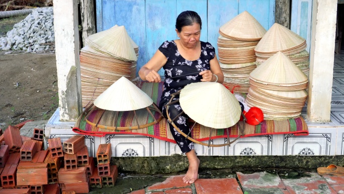 4k镜头的越南老工匠在越南Cantho省Ap Thoi Phuoc村的老传统房子里制作传统越南帽子的