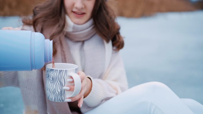 年轻女子将热茶从瓶子倒进杯子的肖像