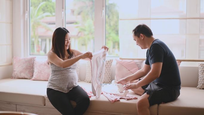 亚洲一名中国孕妇准备迎接新生婴儿，与丈夫一起准备婴儿布和婴儿房