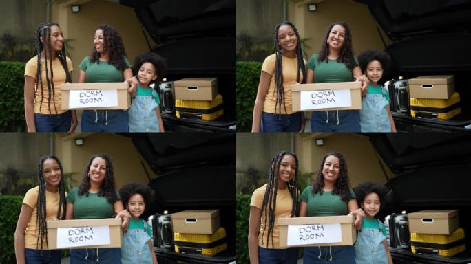 母亲和女儿把卡片盒放进汽车后备箱的肖像
