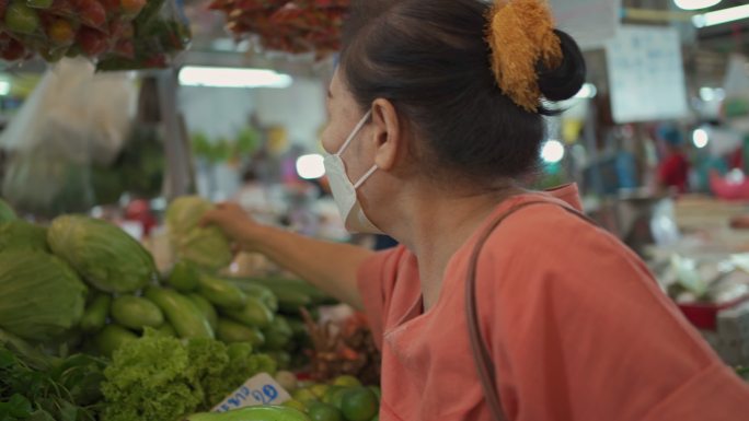 亚洲老年妇女买蔬菜。