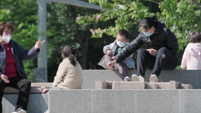 疫情城市公园亲子家庭晒太阳孩子玩滑梯