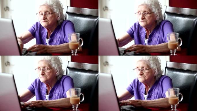 老年妇女在笔记本电脑上打字