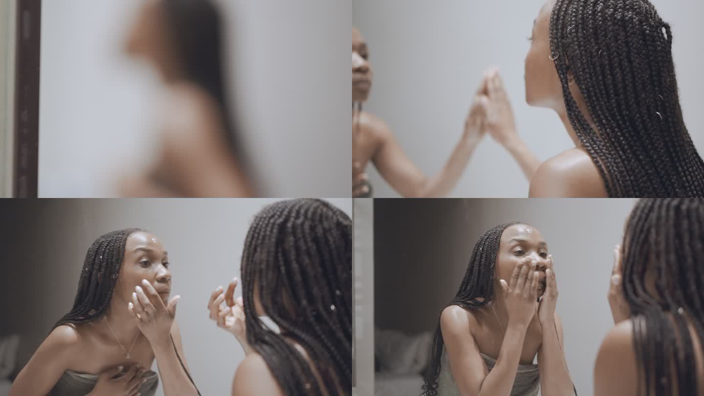年轻女子在浴室镜子里用毛巾洗脸