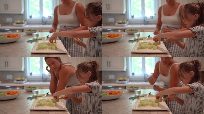 一个年轻的女孩在厨房里帮助她的妈妈。