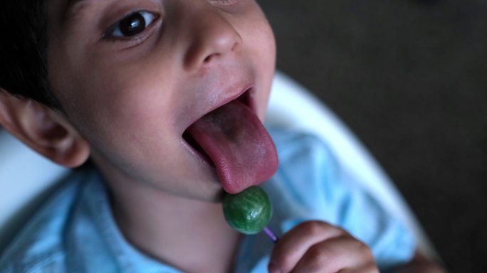 可爱的蹒跚学步的小男孩正在吃棒棒糖。