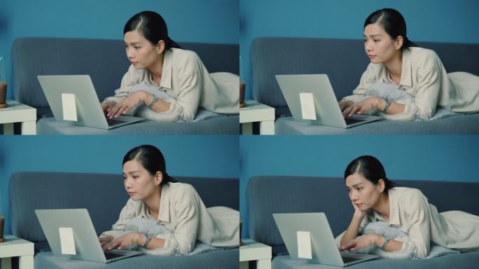 坐在椅子上背痛后躺在沙发上上网学习的亚洲女性。