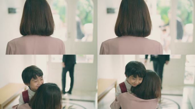 亚洲母亲的后视图正等待着丈夫，丈夫在家里接他们的小儿子放学回家。妈妈拥抱着前门附近的小男孩，欢迎从学