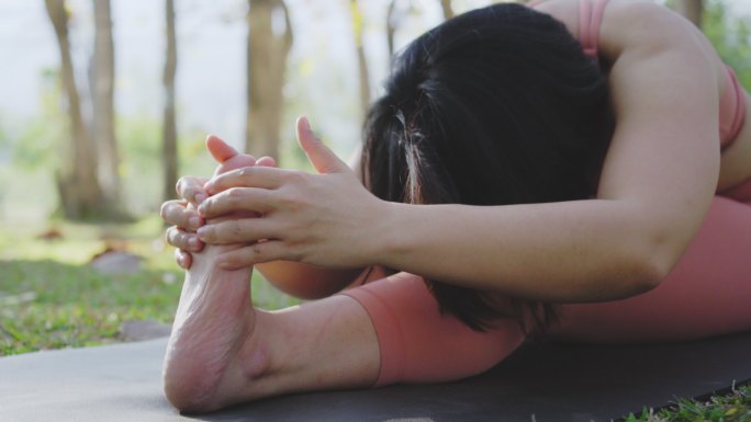 两张瑜伽老师坐在公共公园里伸脚趾的照片