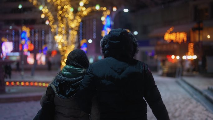 冬天夜里下雪时，年轻的夫妇在城里散步