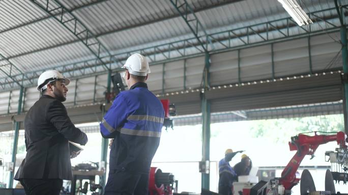员工们在工厂用机器人手臂工作。