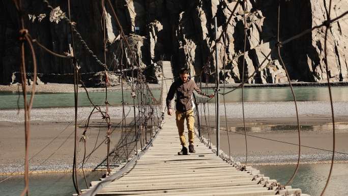 在喜马拉雅山脉吊桥上行走的男子