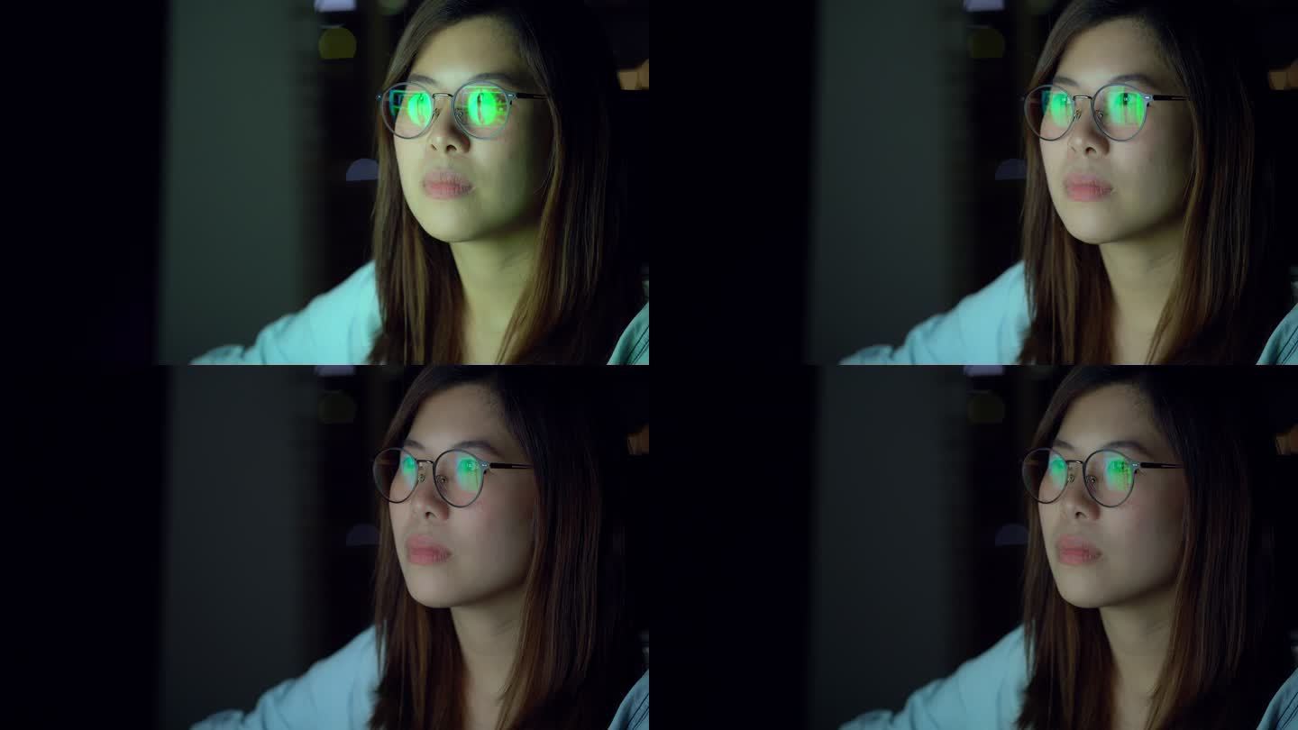4K慢镜头拍摄的迷人的亚洲女性戴着眼镜工作到深夜，认真地看着屏幕，工作到深夜和努力工作的理念