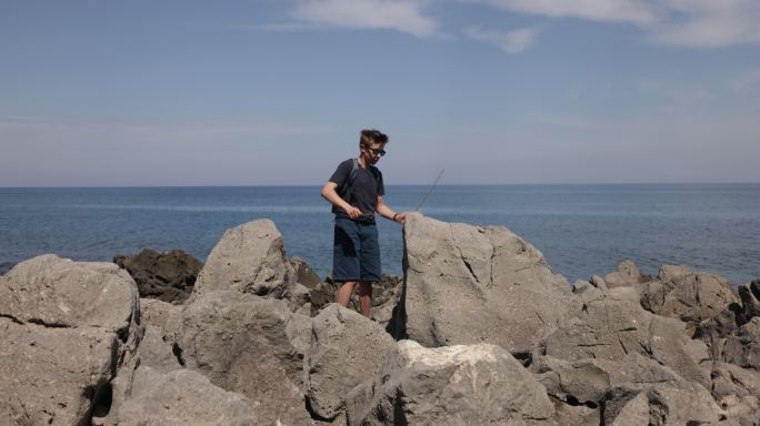 十几岁的男孩在塞法鲁镇和大海之间的岩石上徒步旅行
