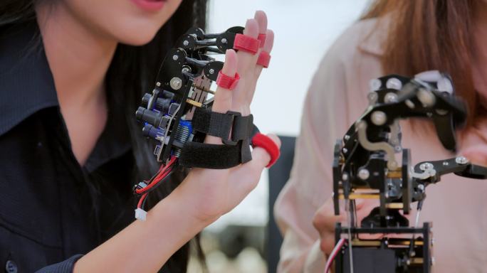特写一个十几岁的女孩在研究实验室里与开发工程师玩得很开心的未来假肢机器人手臂。手臂移动手指。工业4.