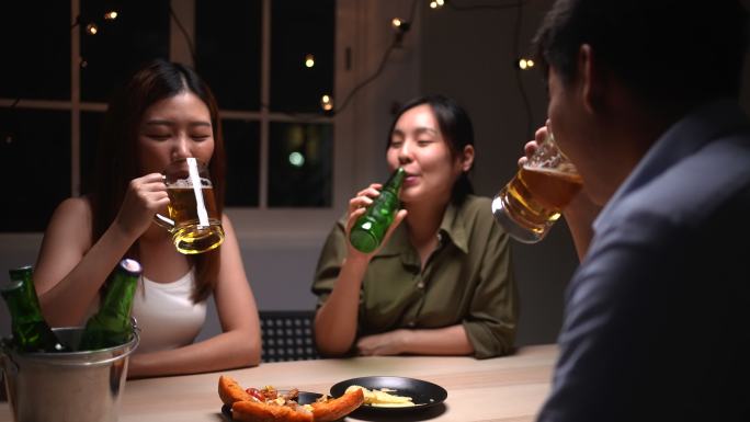 亚洲人正在庆祝节日，他们碰杯啤酒，晚餐快乐