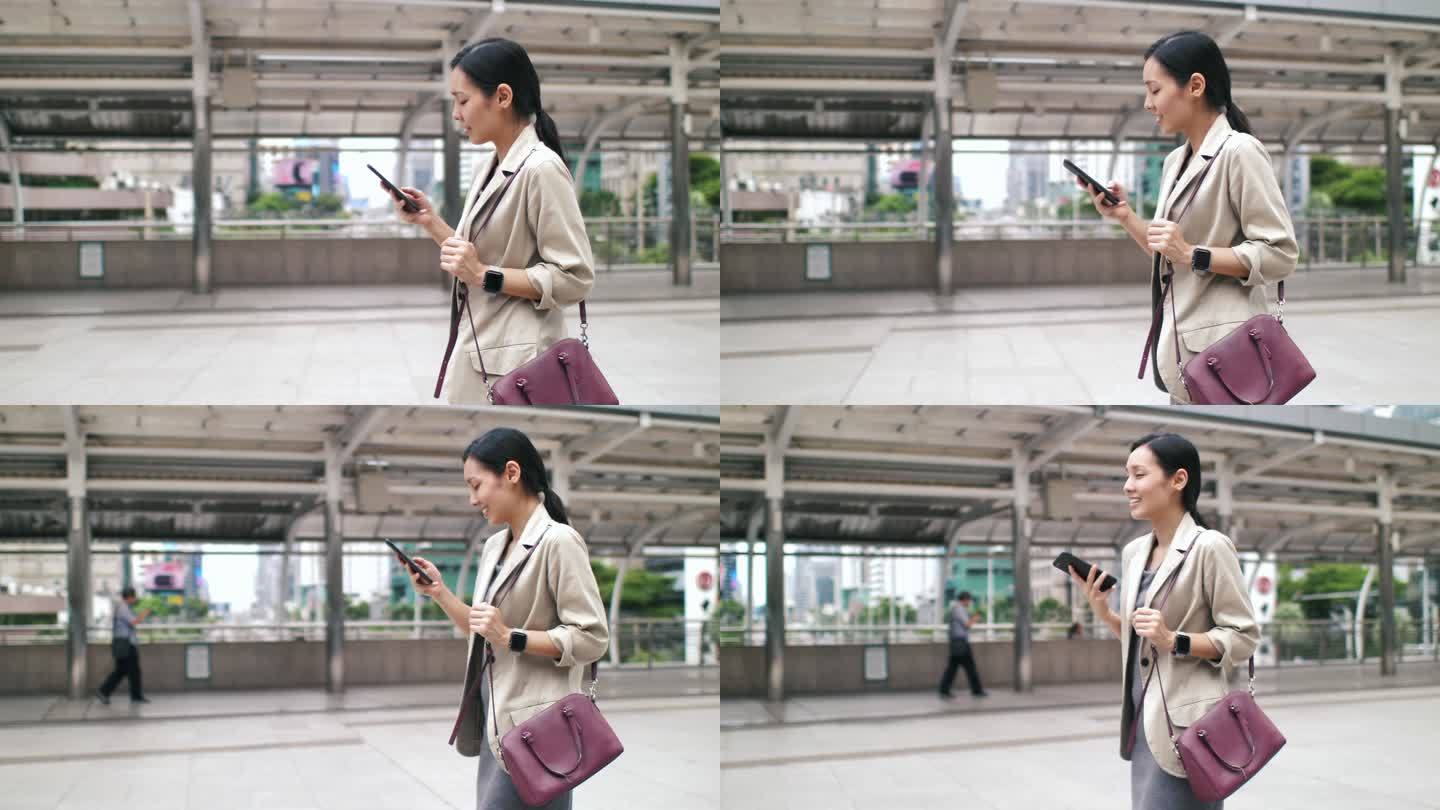 亚洲女性在城市中步行上班时使用智能手机