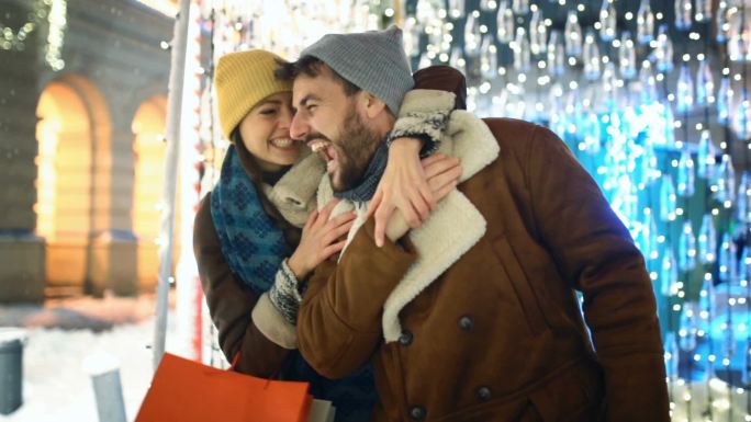 一对情侣在雪夜的圣诞集市上慢镜头。