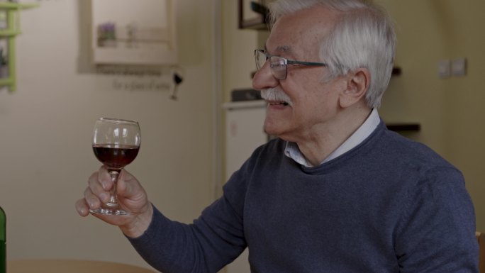 老年男子与妻子一起欢呼，然后喝了一口红酒