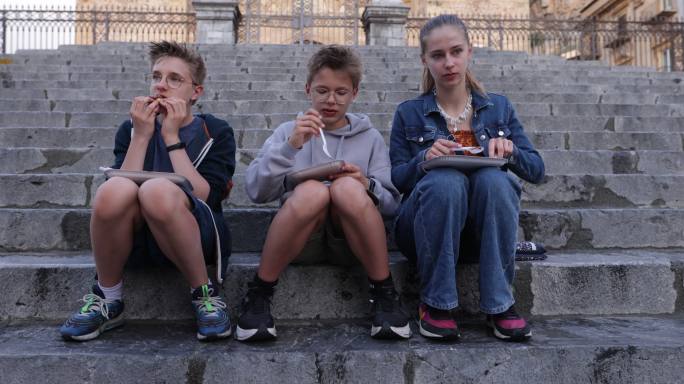 在塞法鲁大教堂的台阶上享用当地街头食品华夫饼的青少年