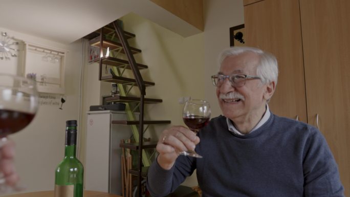 快乐的老人与妻子一起欢呼，然后啜饮红酒