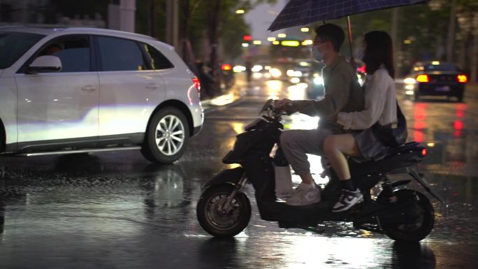 下雨天情侣骑电动车打伞