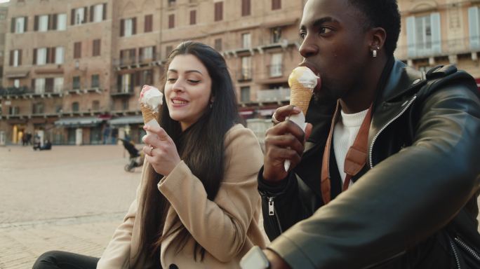 日落时分，年轻的成年夫妇在锡耶纳吃冰淇淋