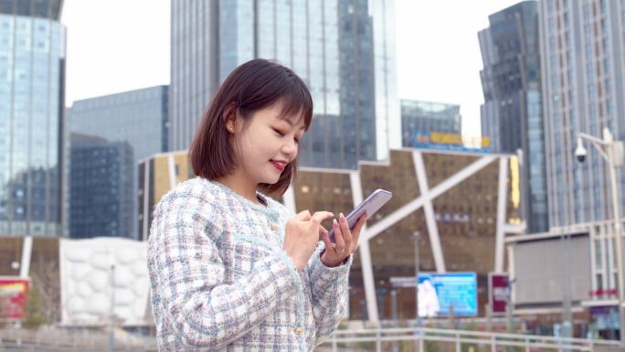 RT/亚洲年轻女性在城市街道使用智能手机