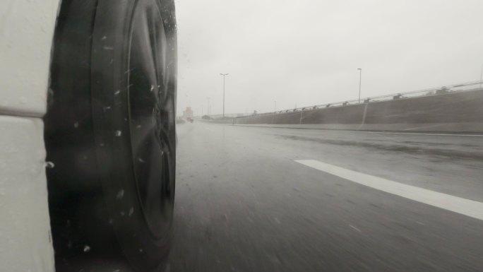 雨天在高速公路上开车。汽车轮胎和飞溅的水