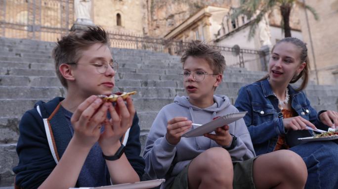 在塞法鲁大教堂的台阶上享用当地街头食品华夫饼的青少年