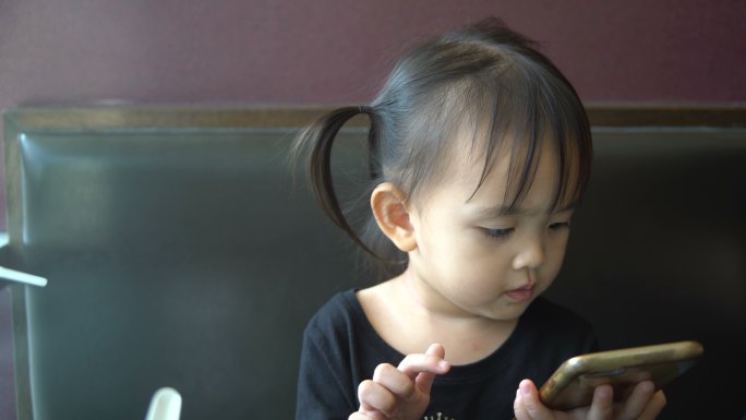 亚洲女孩在餐厅里使用电话。