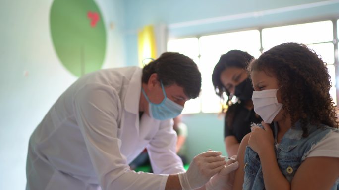 女童在接种中心与母亲一起接种疫苗