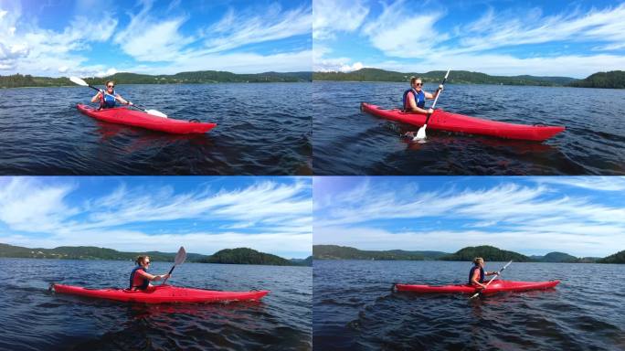 女子划着红色皮划艇，身穿救生衣，天空湛蓝，前景中的女孩划着独木舟