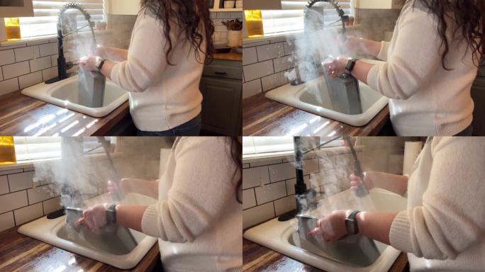 年轻女子在厨房用热蒸汽洗盘子