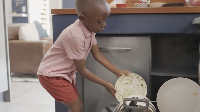 饭后，小男孩帮妈妈装洗碗机