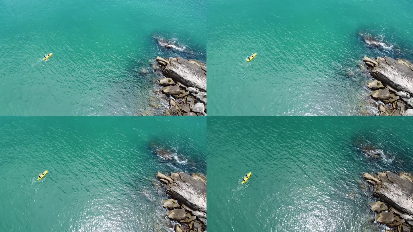 鸟瞰朋友在岩石地层附近的黄色皮划艇上玩耍