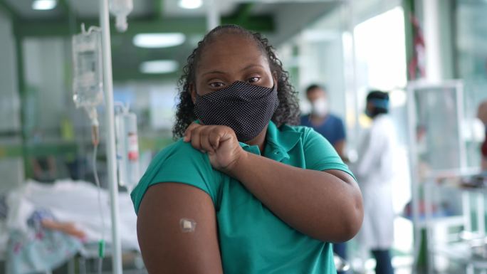 一位有特殊需求的年轻女性在接种疫苗后展示手臂的照片