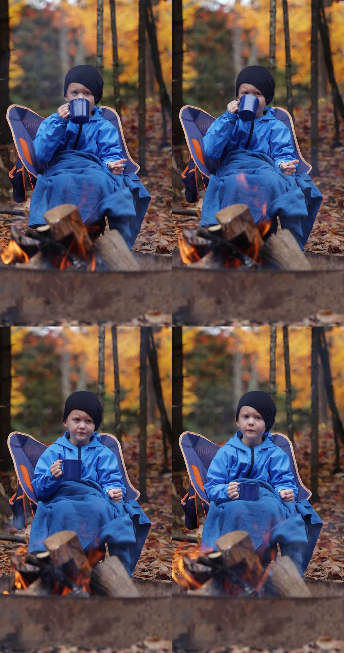可爱的红发男孩在篝火边喝一杯热巧克力秋天户外露营