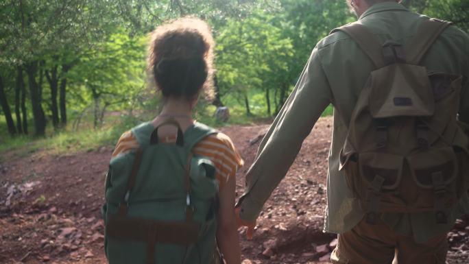 年轻夫妇一起在树林里徒步旅行的后视图