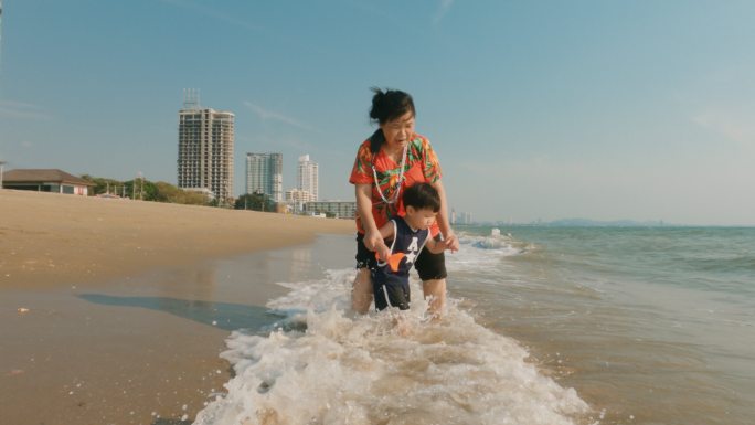 在漫长的周末，快乐的亚洲家庭在海滩上享受时光。