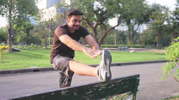 为了健康的生活方式，年轻人在公共公园锻炼前拉伸身体。