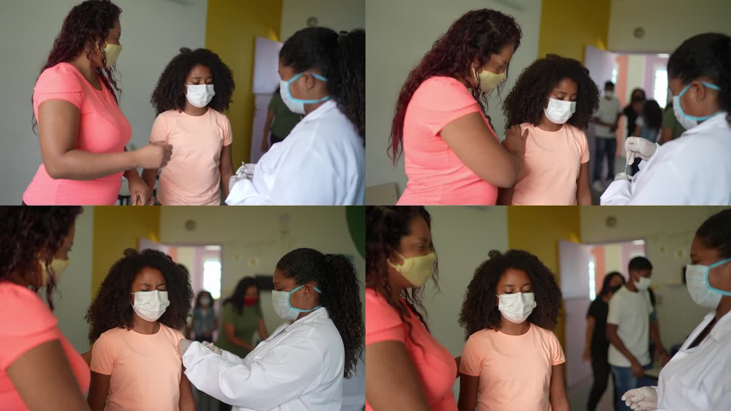 女童在接种中心与母亲一起接种疫苗
