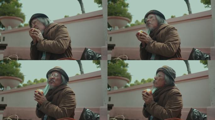 饥饿的无家可归者戴着口罩吃苹果。