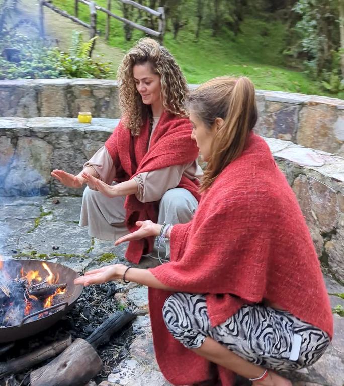 两位拉丁妇女穿着睡衣在酒店阳台上享受篝火带来的自然温暖