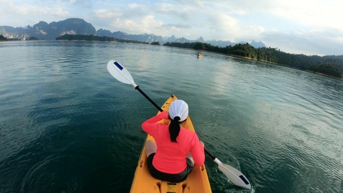 亚洲女子皮划艇在阳光下的热带大湖上午。放松运动